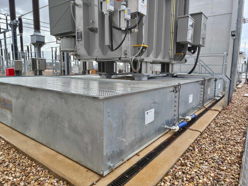 Close-up of a SANERGRID modular tray under a transformer with fire-resistant grating cover and SPI rainwater filtration